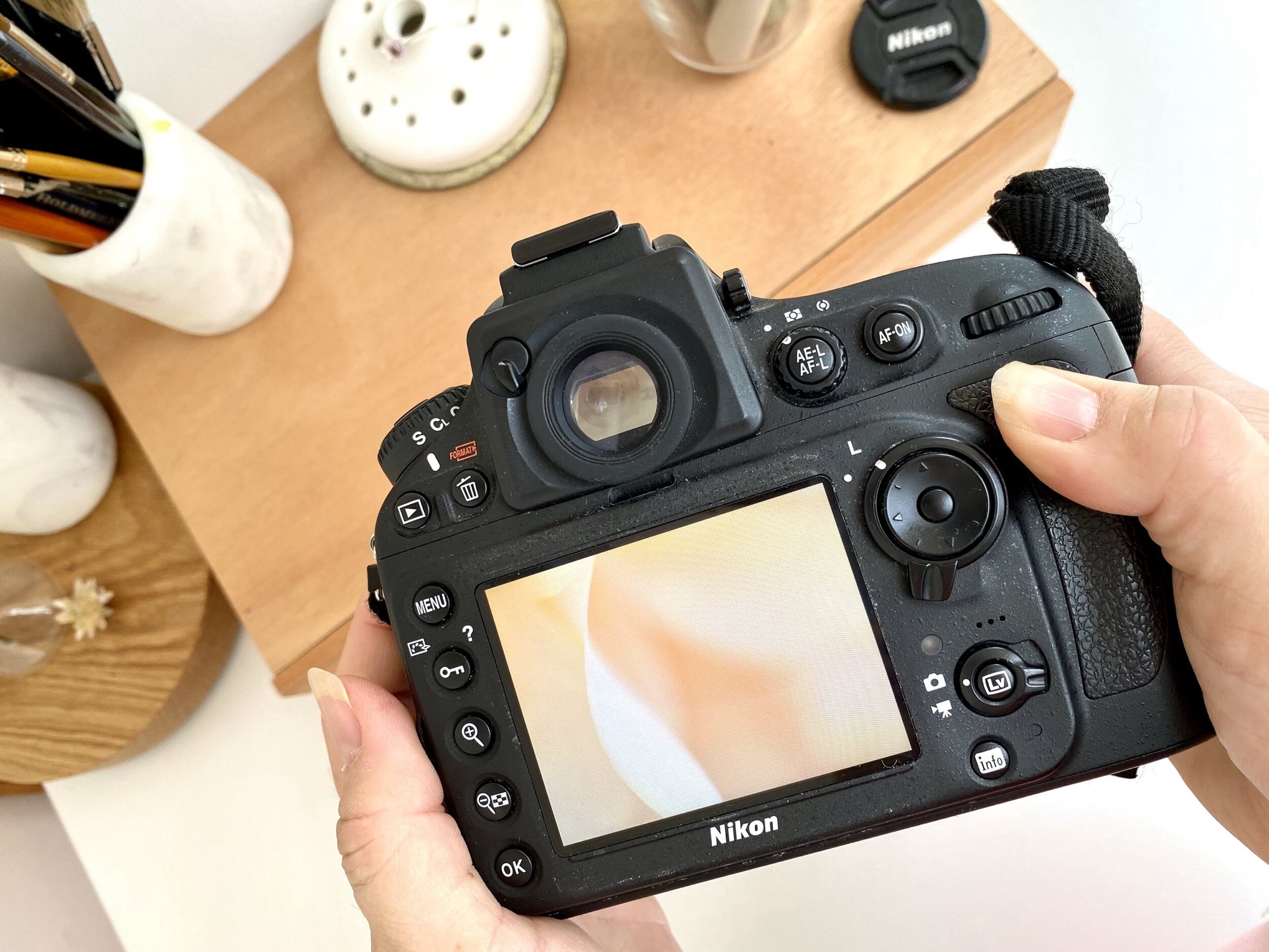 Hands holding a camera showing a soft floral image on its screen